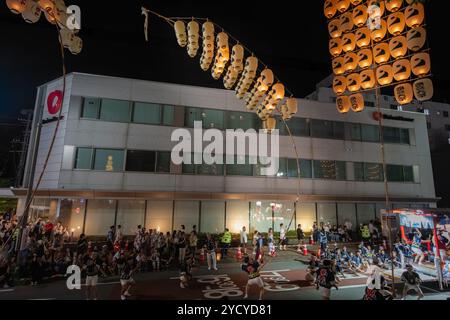 Akita, Japan – 5. August 2024: Eine Gruppe junger Menschen in traditionellen Trachten hält während des lebhaften Akita Kanto Festivals hohe gelbe Laternen. T Stockfoto