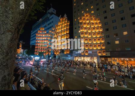 Akita, Japan – 5. August 2024: Eine Gruppe junger Menschen in traditionellen Trachten hält während des lebhaften Akita Kanto Festivals hohe gelbe Laternen. T Stockfoto