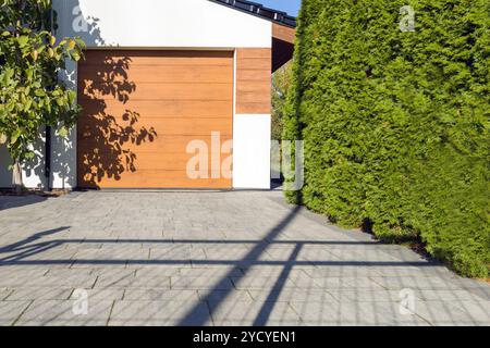 Moderne Garage mit Holztür und grüner Hecke Stockfoto