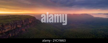 Panorama des magischen Sonnenaufgangs über dem nebelgefüllten Jamison Valley. In der Ferne fangen die einsamen Klippen des Mt das warme Licht. Blue Mountains Australien Stockfoto