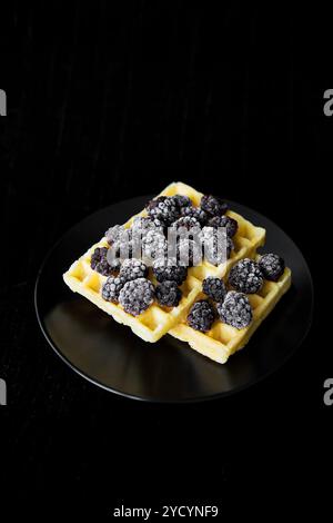 Belgische Waffeln mit Gefrorene Brombeeren auf schwarzem Hintergrund Stockfoto