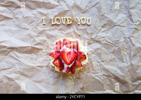 Helle Cupcake mit Erdbeeren liegt auf Handwerk Papier, die Inschrift ich liebe Dich. Stockfoto