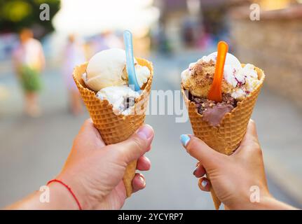 Schönes helles Eis mit verschiedenen Geschmacksrichtungen in den Händen von ein paar Stockfoto