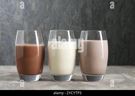 Köstliche Proteinshakes in Gläsern auf grauem, strukturiertem Tisch Stockfoto