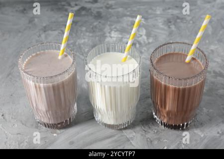 Leckere Proteinshakes in Gläsern auf grauem, strukturiertem Tisch, Nahaufnahme Stockfoto