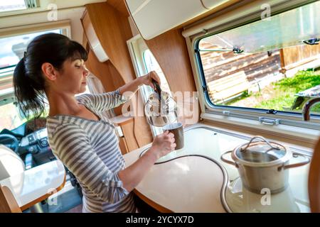 Frau kocht im Wohnmobil, Wohnmobil-Innenraum Stockfoto