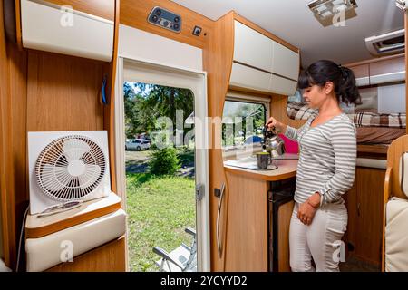 Frau kocht im Wohnmobil, Wohnmobil-Innenraum Stockfoto