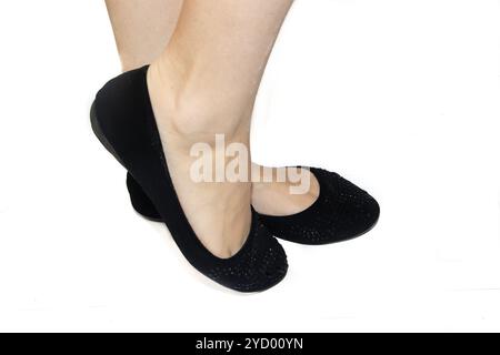 Schwarze Ballettflaches auf weiblichen Beinen auf weißem Hintergrund. Sommerschuhe für Damen. Schwarze Ballerinas auf weißem Hintergras Stockfoto