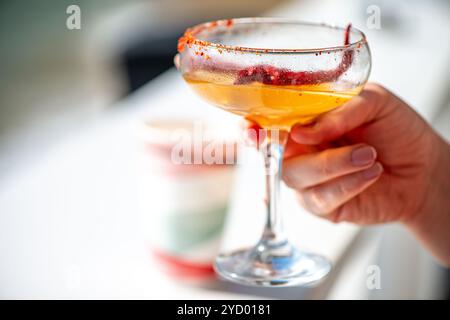Ein lebhaftes Bild einer Frau, die eine scharfe Chili-Margarita genießt und den erfrischenden Geschmack und die farbenfrohe Präsentation des Cocktails in der Hand einfängt. Stockfoto
