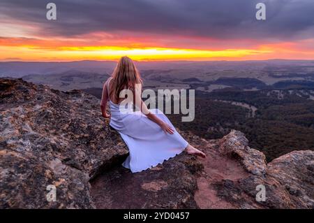 Mädchen in langem weißem Kleid, das den Sonnenuntergang am Mount Blackheath beobachtet Stockfoto