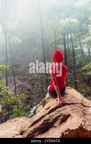 Eine Frau, die sich vor dem Regen in einer Höhle über den Blue Mountains versteckt Stockfoto