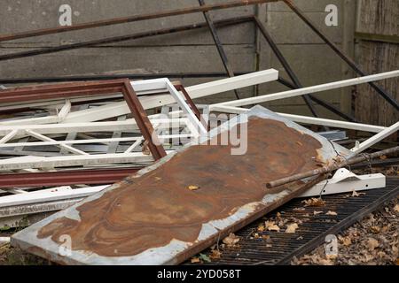 Rostiges Metallblech und verstreute Stahlrahmen in einem Außenbereich, umgeben von Herbstlaub Stockfoto