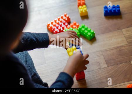 Bunte Kunststoffbausteine auf einem Holzboden, die einen Moment der Kreativität und des Spiels mit lebhaften Farben zeigen Stockfoto