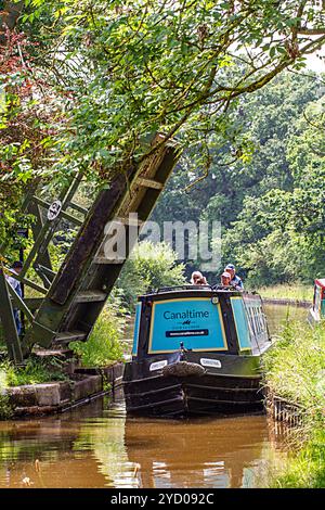 Ein Mann, der ein Schmalboot über eine Liftbrücke auf dem Llangollenkanal bei Whixall Moss bei Whitchurch Shropshire England steuert Stockfoto