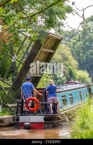 Ein Mann, der ein Schmalboot über eine Liftbrücke auf dem Llangollenkanal bei Whixall Moss bei Whitchurch Shropshire England steuert Stockfoto