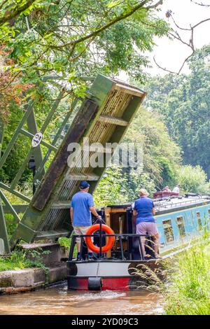 Ein Mann, der ein Schmalboot über eine Liftbrücke auf dem Llangollenkanal bei Whixall Moss bei Whitchurch Shropshire England steuert Stockfoto