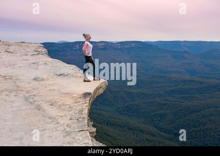 Wanderer, der auf dem Berghang steht und auf das Tal dahinter blickt Stockfoto