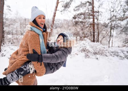 Ein freudiger Moment zwischen Mutter und Kind, die im Schnee spielen und das Wesen des Winterglücks festhalten. Stockfoto