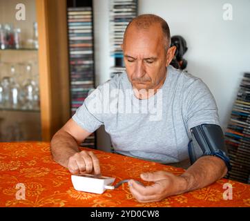 Der Mensch misst seinen eigenen Blutdruck zu Hause selbst. Stockfoto