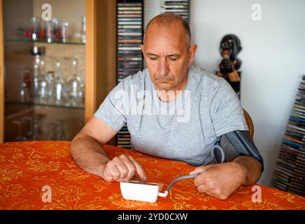 Der Mensch misst seinen eigenen Blutdruck zu Hause selbst. Stockfoto