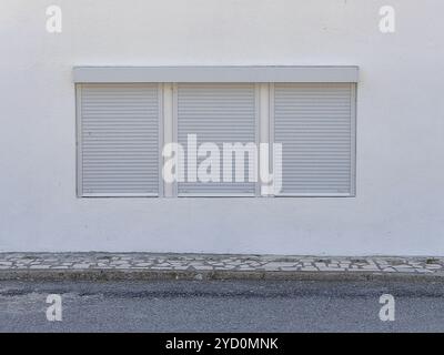 Moderner Minimalismus: Dreifache Fensterrahmen mit weißen Jalousien an der Wand zur Straße Stockfoto