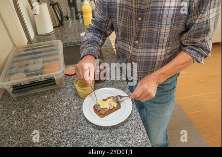 Ein Mann, der an einer Küchentheke steht und ein dänisches Heringssandwich mit Currysalat auf einem Roggenbrot zubereitet, Dänemark, 24. Oktober 2024 Stockfoto