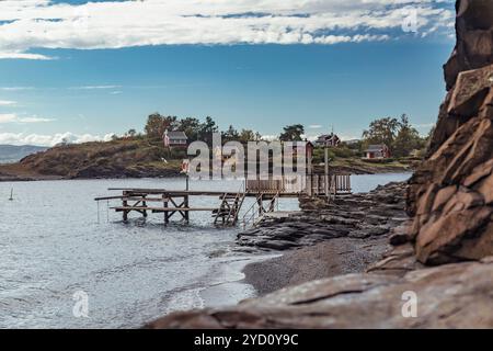 Erkunden Sie die ruhige Schönheit der Lofoten-Inseln, wo sich ein bezaubernder Dock in das ruhige Wasser erstreckt, umgeben von rustikalen Häusern und atemberaubender Natur Stockfoto