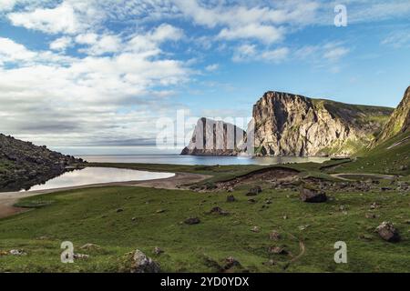 Erkunden Sie die atemberaubende Schönheit des Kvalvika-Strandes auf den Lofoten-Inseln, wo majestätische Klippen auf ruhiges Wasser unter einem lebendigen Himmel treffen, perfekt zum Wandern Stockfoto