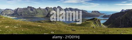 Erkunden Sie die atemberaubende natürliche Landschaft der Lofoten Inseln mit sanften Hügeln, schneebedeckten Bergen und ruhigen Gewässern, die ein schönes Bild widerspiegeln Stockfoto