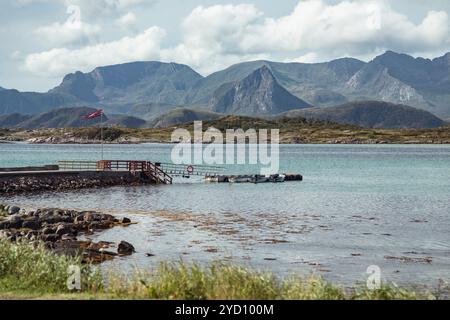 Ein ruhiger Moment fängt die Schönheit der Lofoten-Inseln in Nordland, Norwegen ein, mit ruhigem Wasser, einem bezaubernden Bootssteg und den majestätischen Bergen in der Stockfoto