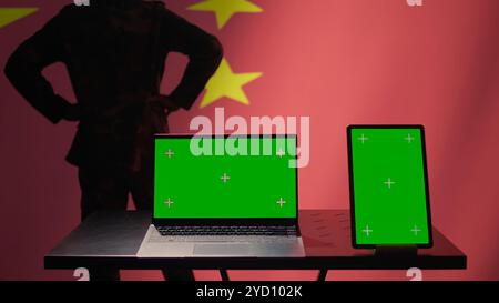 Chinesische Armee Soldat mit isoliertem Bildschirm Laptop und Tablet, um Bedrohungen von Feinden zu identifizieren. Militärangehörige benutzen Software auf Chroma-Schlüsselgeräten, um Informationen an die Front des Krieges weiterzugeben, Kamera B Stockfoto
