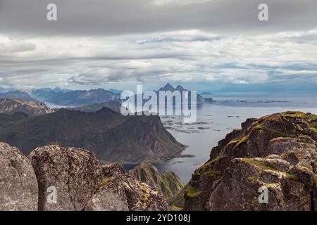 Diese atemberaubende Szene fängt die dramatische Küste der Lofoten-Inseln in Nordland, Norwegen, mit zerklüfteten Klippen, einem ruhigen See und der Distanz ein Stockfoto