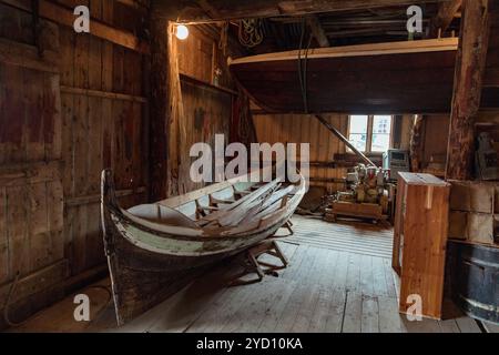 In einer rustikalen Werkstatt auf den Lofoten-Inseln ruhen traditionelle Holzboote unter warmer Beleuchtung aus, die Norwegens tiefes Fischererbe und Naut widerspiegeln Stockfoto