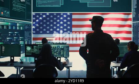 Amerikanisches Militärpersonal, das Serverschutz und geheime Informationen sicherstellt, Staatsgeheimnisse in High-Tech-Agenturbüros schützt. Der Armeesoldat überwacht die Hacker-Aktivitäten. Kamera B.. Stockfoto