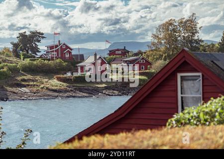 Die ruhige Seeufer in Oslo bietet bezaubernde rote Cottages, umgeben von üppigem Grün und felsigen Ufern, die einen malerischen Urlaub im Frühling schaffen Stockfoto