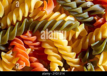 Ungekochte Fusilli Pasta in leuchtenden Farben: Eine faszinierende kulinarische Leinwand aus bunten Spiralen, die einen lebendigen und strukturierten Hintergrund für Gourmet-Kochen schafft. Farbige Trockene Pasta. Rohe Makkaroni Stockfoto