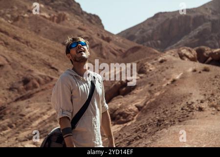 Zwei Abenteurer erfreuen sich an der atemberaubenden Landschaft der marokkanischen Region Makhtesh, umgeben von dramatischen Hügeln und pulsierenden Felsformationen unter einem Stockfoto