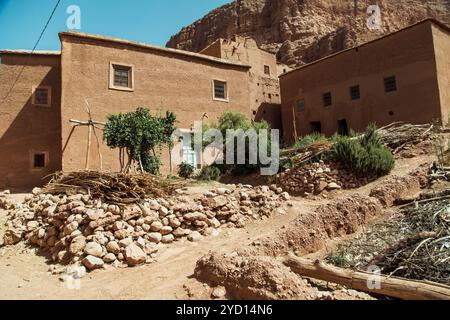 Traditionelle lehmziegelhäuser sind in einem sonnenverwöhnten Tal in Marokko zu sehen, umgeben von zerklüftetem Gelände und Vegetation. Dieses historische Dorf zeigt hu Stockfoto