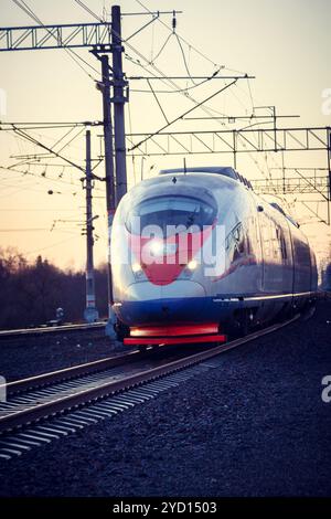 Die Lokomotive fährt bei Sonnenuntergang auf der russischen Eisenbahn. Russische Eisenbahn. Eisenbahn bei Sonnenuntergang. Russland, Leningrad, das Dorf Stockfoto