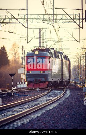 Die Lokomotive fährt bei Sonnenuntergang auf der russischen Eisenbahn. Russische Eisenbahn. Eisenbahn bei Sonnenuntergang. Russland, Leningrad, das Dorf Stockfoto