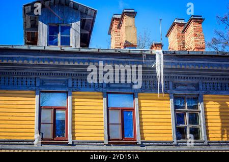 Eiszapfen hängen vom Dach des Hauses. Gefrorenes Wasser. Wasser tropft vom Dach. Stockfoto