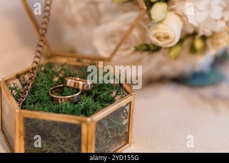 Elegante Hochzeitsringe in Glasbox mit Blumenanordnung. Stockfoto