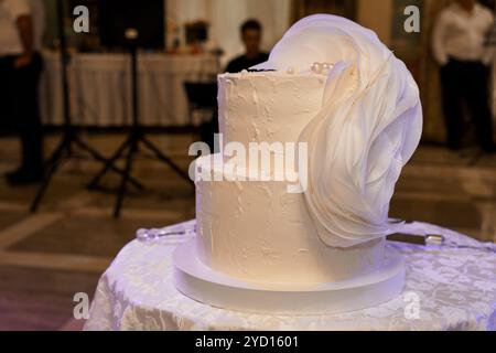 Eleganter dreistufiger Hochzeitstorte mit weißem Fondant und dekorativem Wirbel. Stockfoto