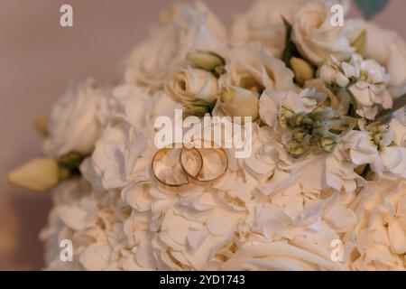 Elegante Hochzeitsringe in einem Blumenstrauß aus weißen Rosen. Stockfoto