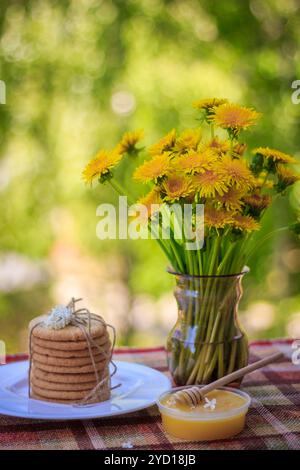 Ein Stapel Kekse, ein Teller Honig und Blumen. Essen und Trinken. Snack in der Natur Stockfoto