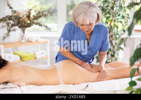 Professionelle Seniormasseuse bei der Anti-Cellulite-Oberschenkelmassage bei der jungen Frau Stockfoto