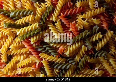 Ungekochte Fusilli Pasta in leuchtenden Farben: Eine faszinierende kulinarische Leinwand aus bunten Spiralen, die einen lebendigen und strukturierten Hintergrund für Gourmet-Kochen schafft. Farbige Trockene Pasta. Rohe Makkaroni Stockfoto