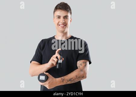 Junger Mann mit Tätowierspray und Creme auf hellem Hintergrund Stockfoto