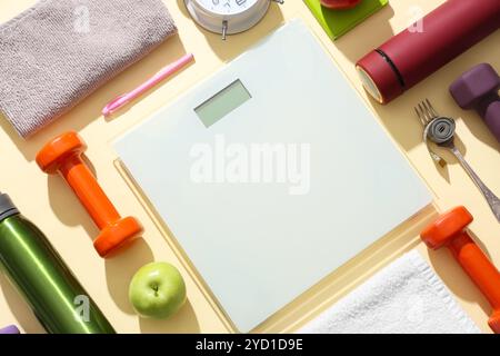 Waage mit Wasserflaschen, Handtüchern und Hanteln auf beigefarbenem Hintergrund. Gewichtsverlust-Konzept Stockfoto