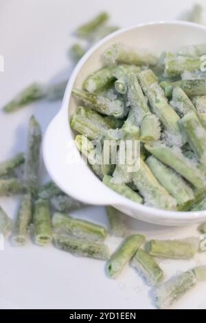 Gefrorene grüne Bohnen auf einem weißen Teller. Gesunde Ernährung. Grünes Gemüse. Vorbereitung zum Kochen. Stockfoto